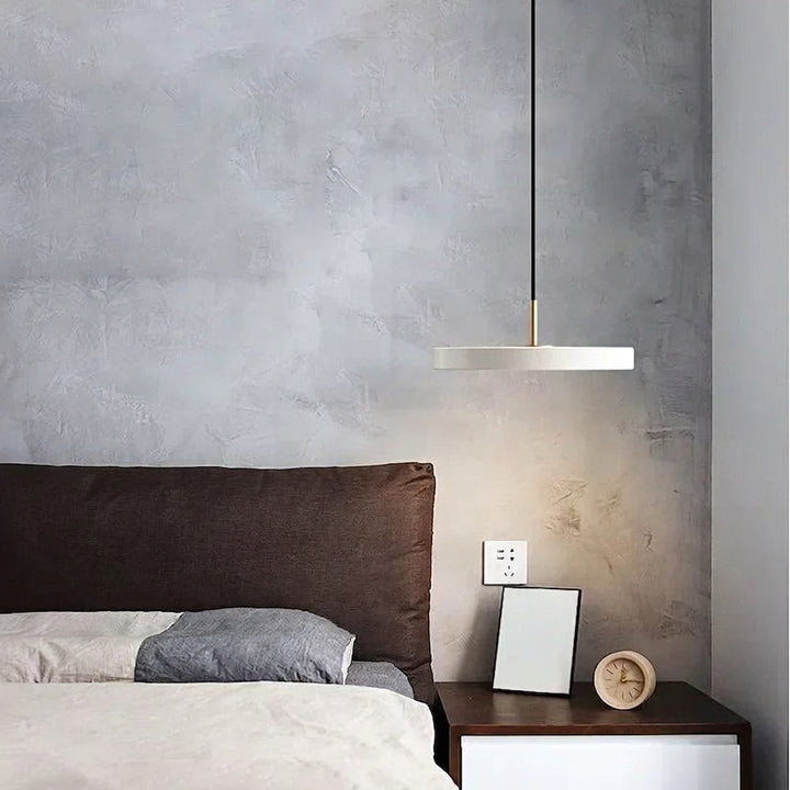 White Scandinavian disc pendant light over a bed